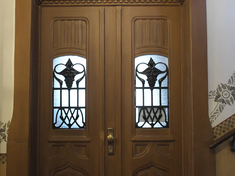 Doppelflügelige Holztür mit ornamentalen Glasfeldern in einem Altbau-Treppenhaus