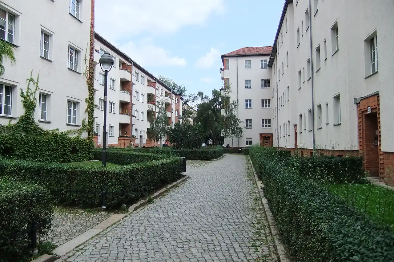 Gepflasterter Weg zwischen Hecken und Altbauten in Lichtenberg