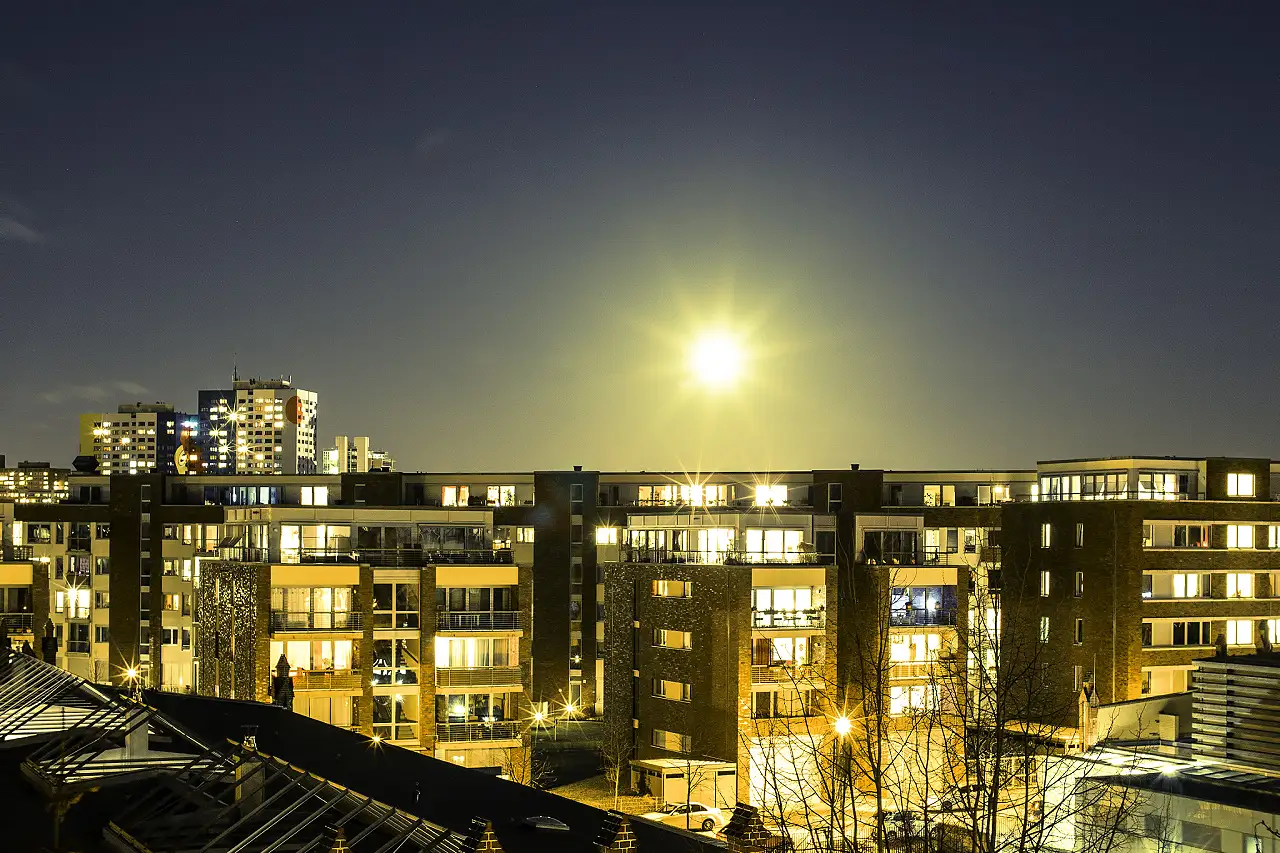 Mond über beleuchteten Häuserblocks in Lichtenberg bei Nacht