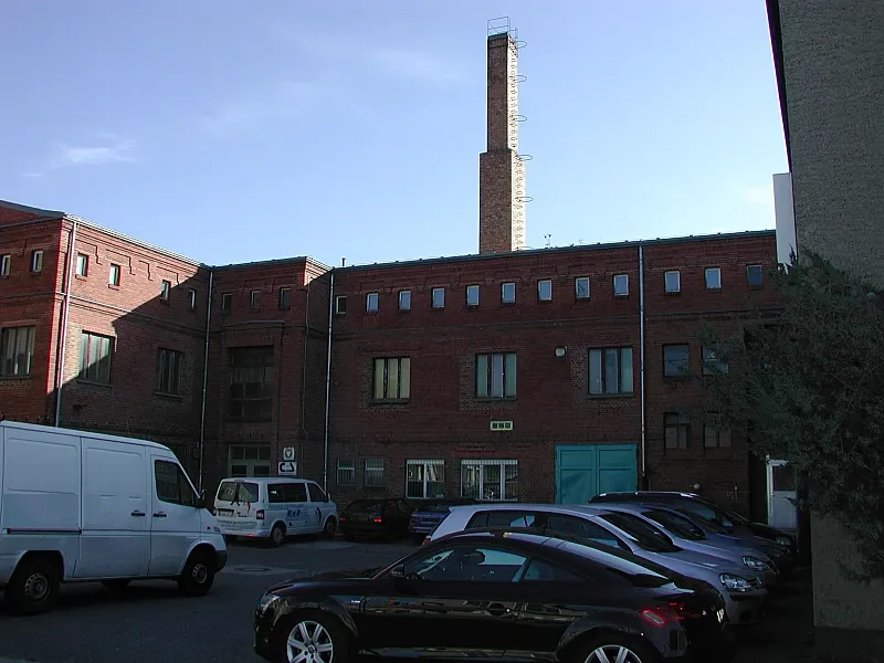 Backstein-Gewerbehof mit Schornstein und Parkplatz im Hof