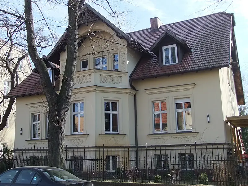 Gelbe Villa mit Ziegeldach und Vorgarten